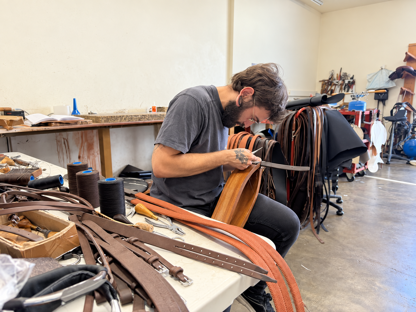 Artisan cousant une pièce de briderie dans l'atelier Sellerie Cassou