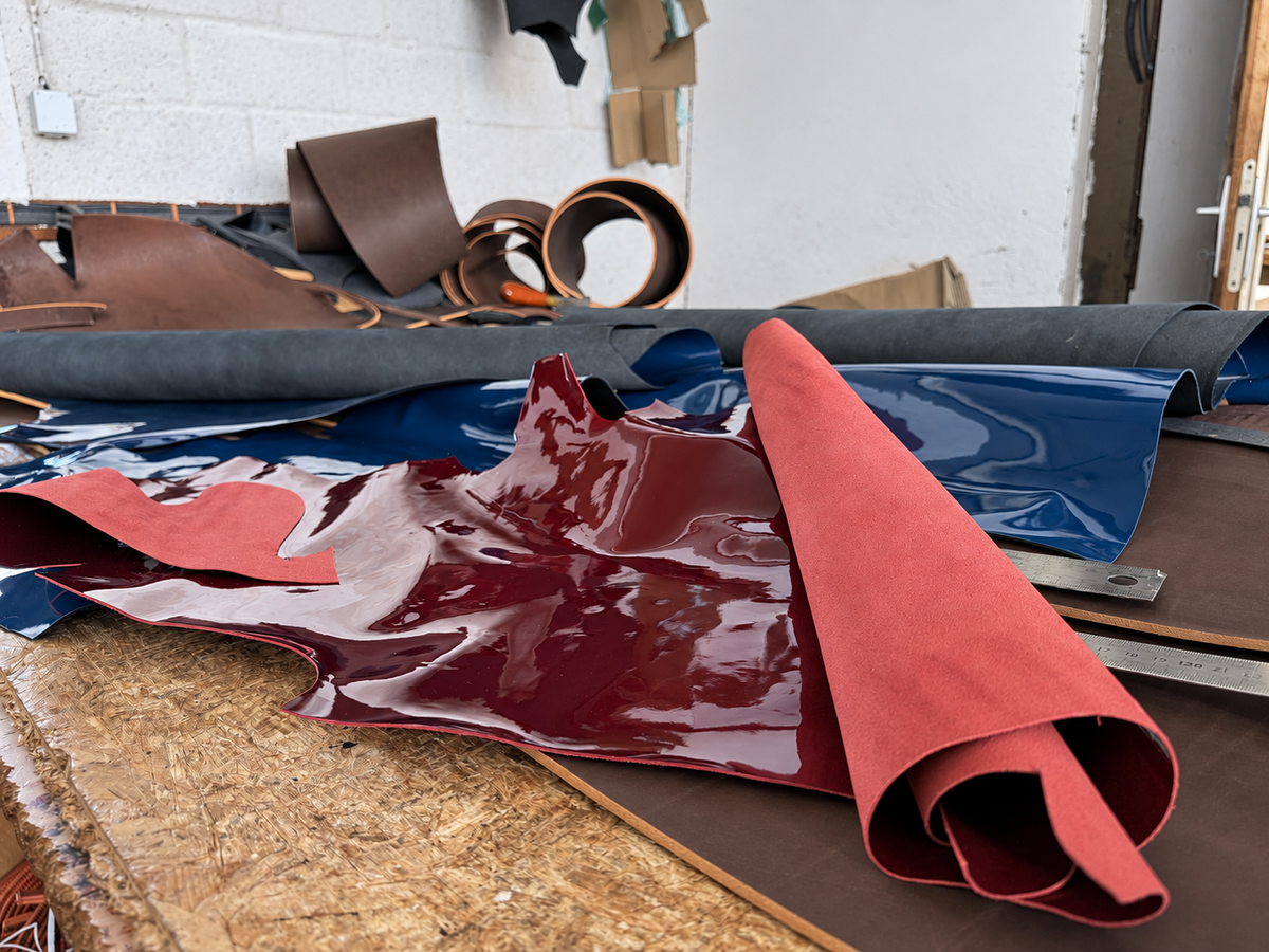 Burgundy and blue patent leather and other materials on the cutting table.