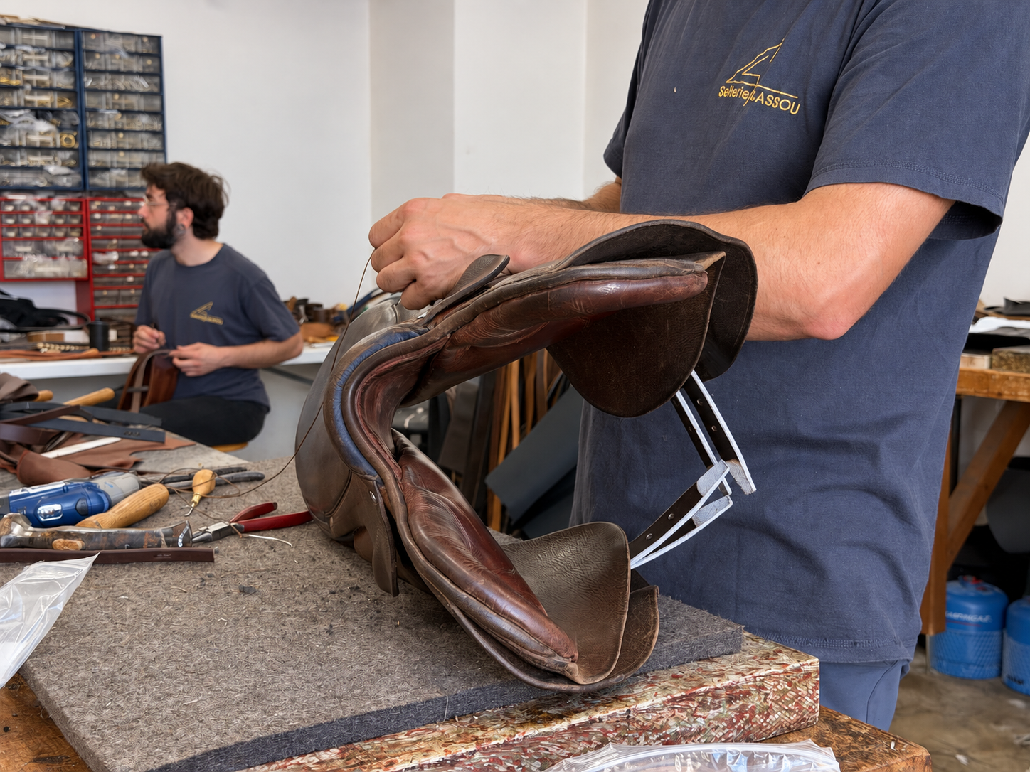 Détail d'une selle en cuir tenue et examinée dans l'atelier Sellerie Cassou.